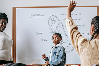 Black children are in a classroom with a Black teacher.