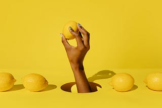 Yellow background with a hand holding a lemon