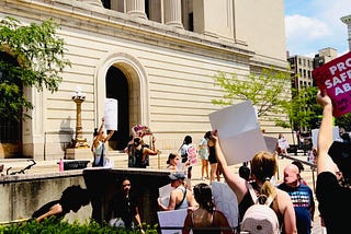 As she stood fierce, pitched forward atop the Hamilton County Courthouse steps, arms high with her…