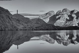 Photo of mountain, moon, and water in reflection.