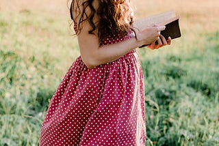 A Girl in the field reading a book