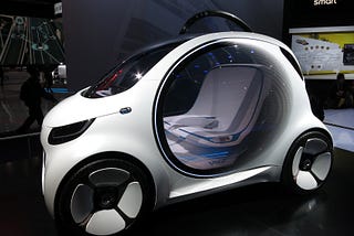 A futuristic small white car with a circular door that is transparent, looking like it’s made out of glass with two seats inside.