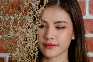 close-up-young-beautiful-attractive-asian-female-model-s-face-with-flower-s-branch-against-orange-brick-wall-background — Un Swede