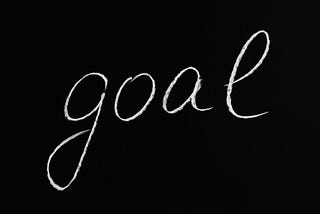 Image of “Goal” written on a chalk board. Setting goals starts with first assesing your year.