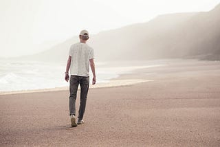 Young man walking alone on the beach