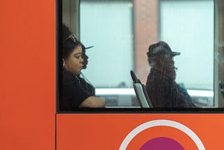 A woman looking out the window while riding on a public city bus