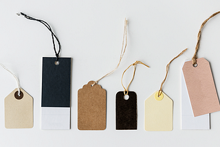 Clothing tags of different sizes and colours are exposed on a white surface