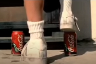 Um menino sobe em duas latinhas de Coca-Cola.