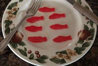 A Christmas plate with fork and knife. 7 gummie candy fishes included