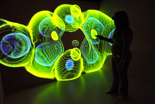 The image shows the silhouette of a person in front of a yellow, green and blue “jellyfish” representation of data.