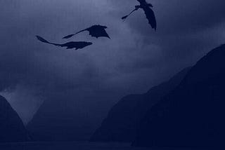 Three dragons flying over mysterious mountains on a dark cloudy night.