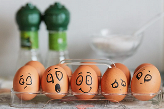 A set of eggs with drawn faces — some happy, some sad, some scared