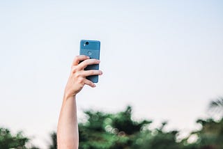 A hand holding a smartphone in the air