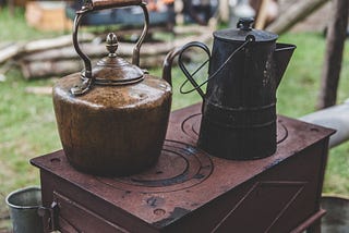 Image of a metallic jar and metallic kettle on a stove.