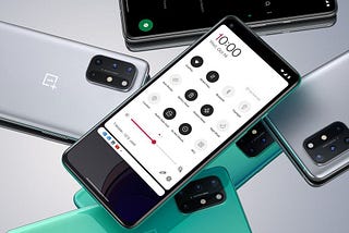 A promotional image of a phone, the OnePlus 8T, displaying a quick settings menu on the screen. Several other OnePlus 8T phones lie face down beneath it.