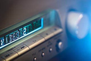 Image shows part of the blue display of a silver-colored stereo tuner.
