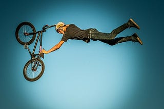 A man flies through the air with his bicycle.