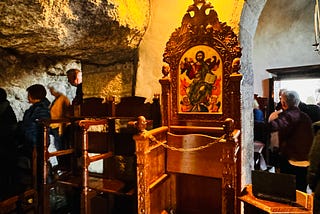 A cave is shown with people inside it. Ornate chairs are shown in the front