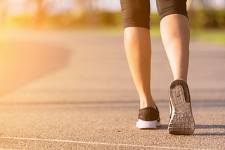 a woman’s legs and feet dressed in activewear shown walking on concrete