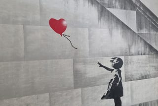 Banksy’s ‘Girl with Balloon’. A red heart-shaped balloon blowing away from a forlorn little girl.