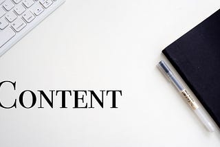 White table with black notebook, keyboard and the word content