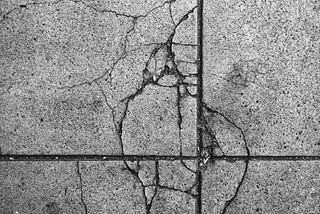gray sidewalk with man-made and nature-made cracks