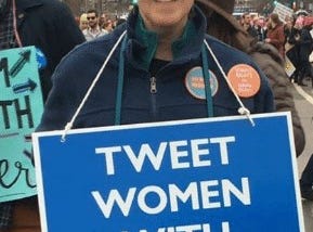 Woman holding a blue sign with “TWEET WOMEN WITH RESPECT” in white lettering