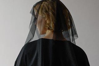 Picture of a woman dressed in black funeral style clothing.