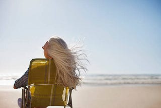 White-haired woman in beach chair watching the ocean.