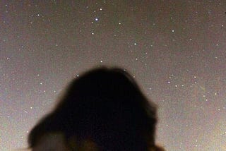 A silhouette of a girl staring up at the stars.