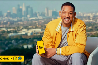 Will Smith sorrindo, sentado em uma poltrona clara, vestindo jaqueta amarela, segurando um smartphone com tela amarela exibindo um logotipo estilizado. Ao fundo, uma vista ampla de uma cidade com prédios ao longe. No canto inferior esquerdo, há uma faixa amarela com os logotipos “Nomad” e “L3TI”.