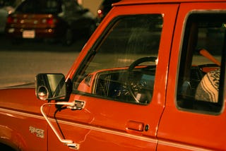 tightly-framed photo of an old red pickup truck late at night