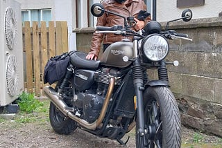 Female pillion standing next to Triumph Street Twin 900 motorbike after first ride