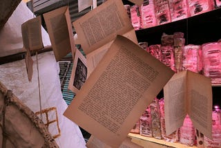 Details of an art installation, with book pages suspended in the foreground.