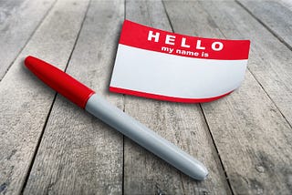 “Hello, my name Is” sticker and pen on table