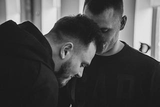Two men, leaning in towards each other, sharing a tender moment.