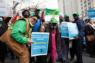 Human Service workers holding signs that read “Just Pay, Livable Wage and Labor Peace”