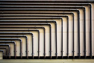 Pipes on a wall form geometric shapes.