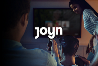 Picture of three people in front of a TV. The word “Joyn” is in the middle of the picture.