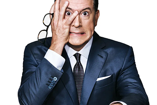 Stephen Colbert has a frustrated angry look on his face as he hides half his face in his hands and holds his glasses. Comedy, Late Show, Colbert, Fallon, democracy, anarchy, shooting in Minneapolis, unrest, law and order, protest