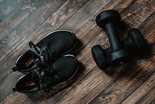 Black sneakers and hand weights on a wooden floor