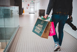 A man walks through a mall holding shopping bags