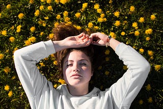 Woman daydreaming while lying in a field of yellow flowers