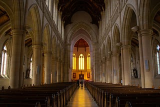 View from the back of a church with lighted windows.