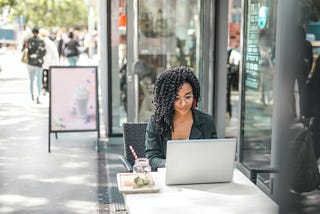 A Woman Sitting Outside a Cafe Working on Her Computer