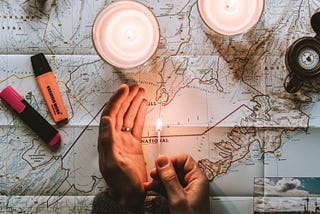 Two hands lighting up a large map of Iceland with a match