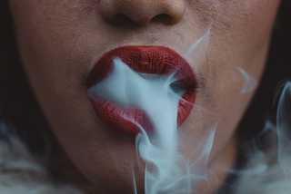 Ladies mouth with red lipstick smoking.