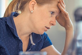 Woman rubbing her forehead looking confused