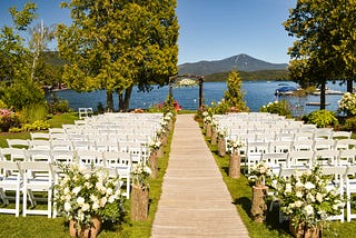 Wedding venue with white empty chairs at a nearby lake overlooking a mountain.