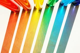 Coloured water in glass tubes with light shining behind them, creating coloured lines in front of the tubes.